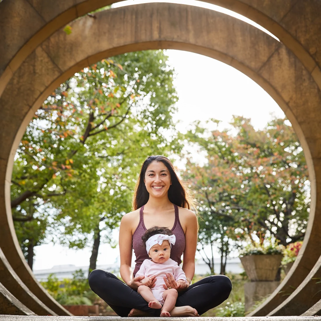 Miné seated with a baby in a calm family yoga portrait